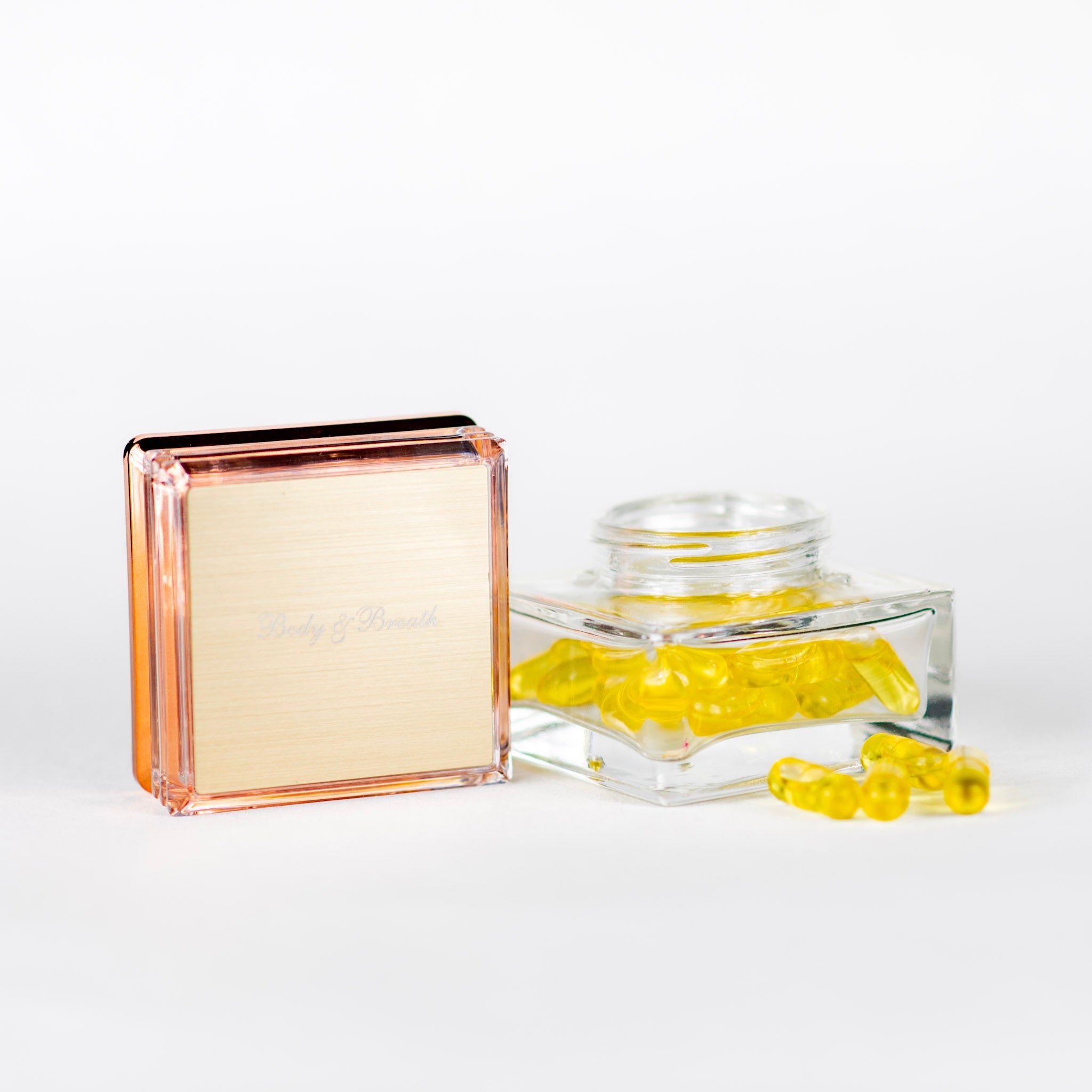 Läbipaistev anum kollaste kapslitega valgel taustal.