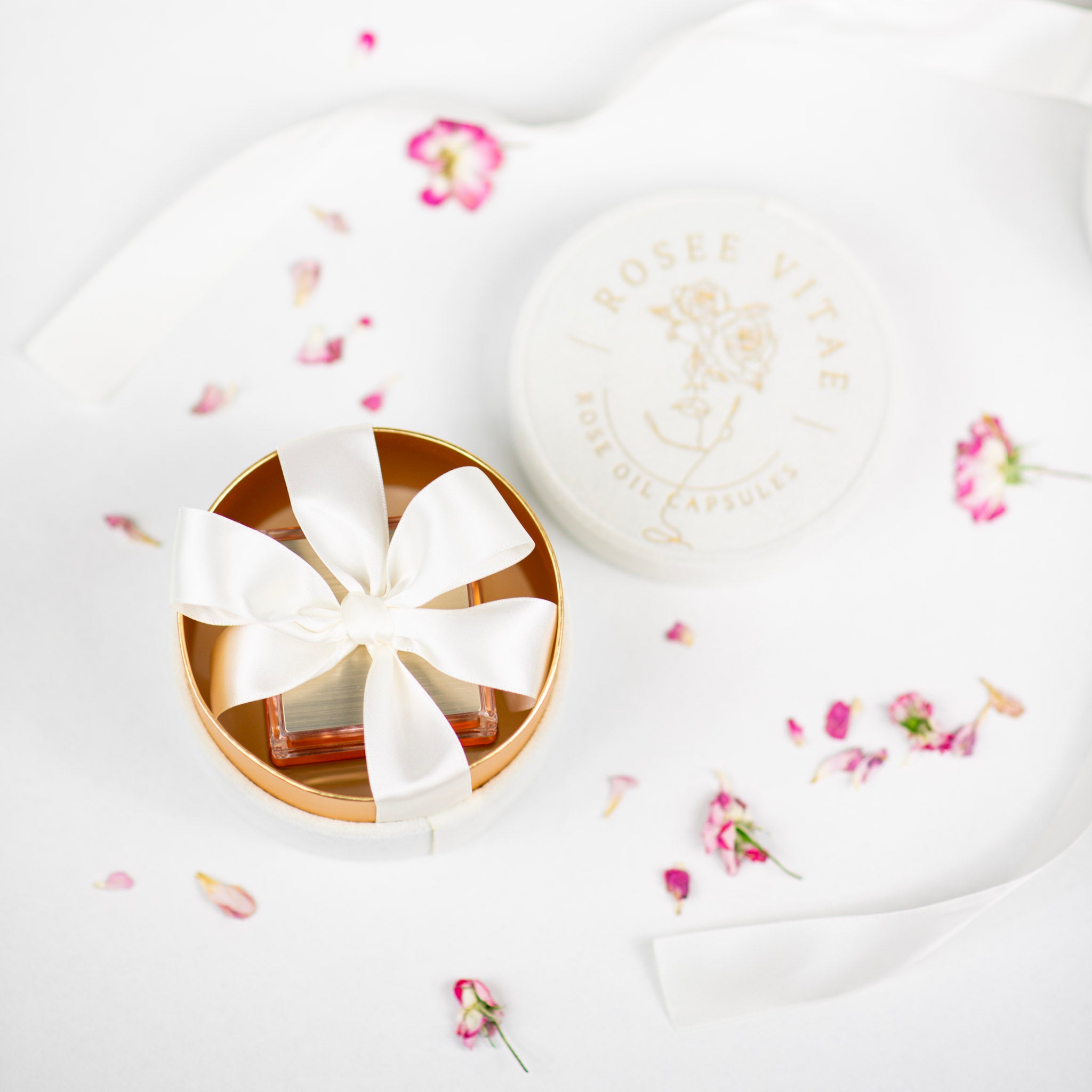 Väike ümmargune anum valge lipsuga heledal pinnal, laiali puistatud lilledega.