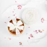 Väike ümmargune anum valge lipsuga heledal pinnal, laiali puistatud lilledega.