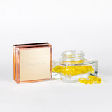 Läbipaistev anum kollaste kapslitega valgel taustal.