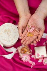 Ristuvad käed mille peal roosiõis koos kapslitega.